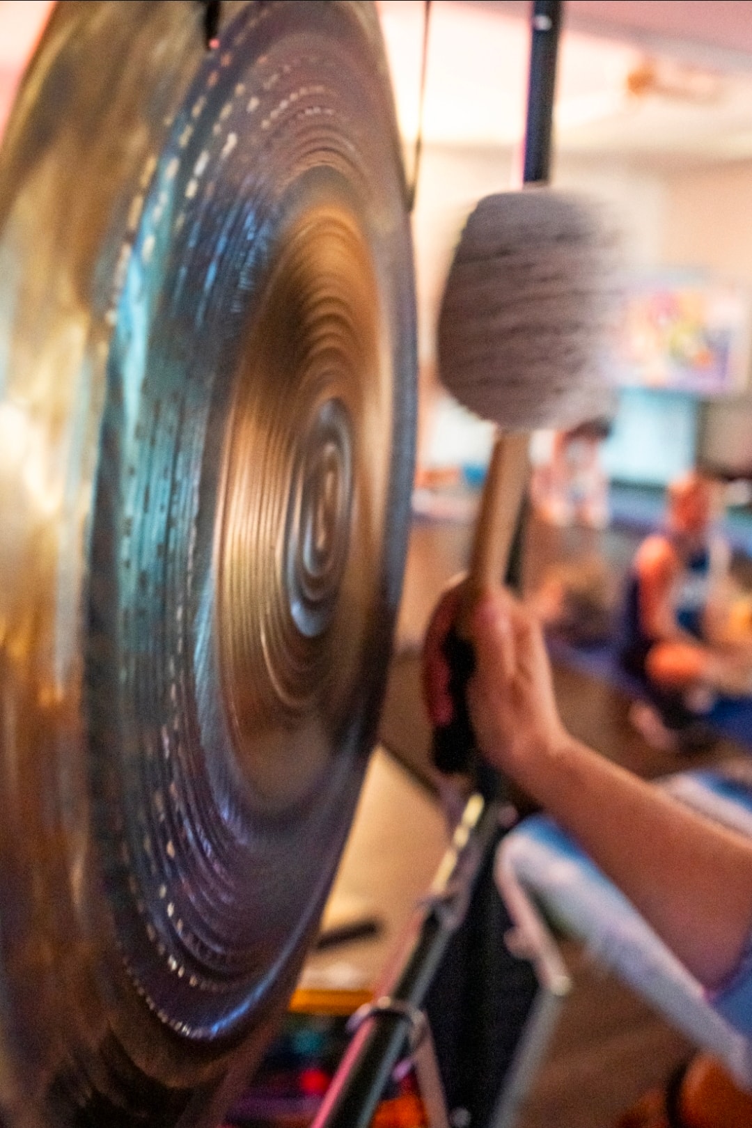 Practitioner playing a large gong during a sound healing ceremony