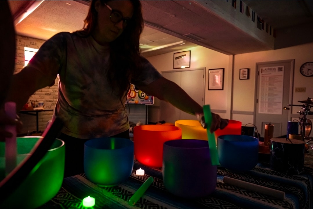 Practitioner playing colorful crystal singing bowls during a sound bath session
